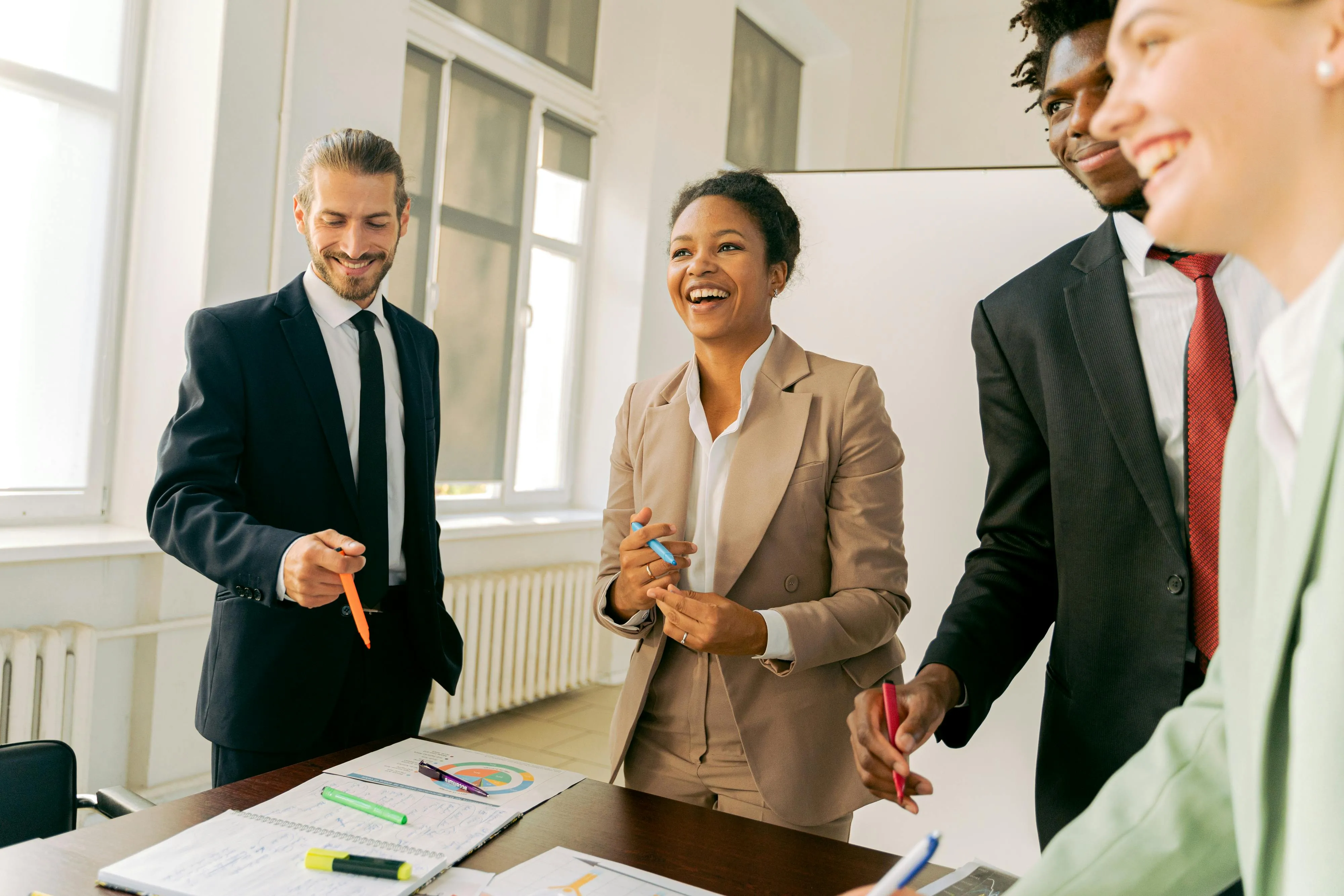 Six arms and hands piled up in the middle on top of each other over a business meeting table.