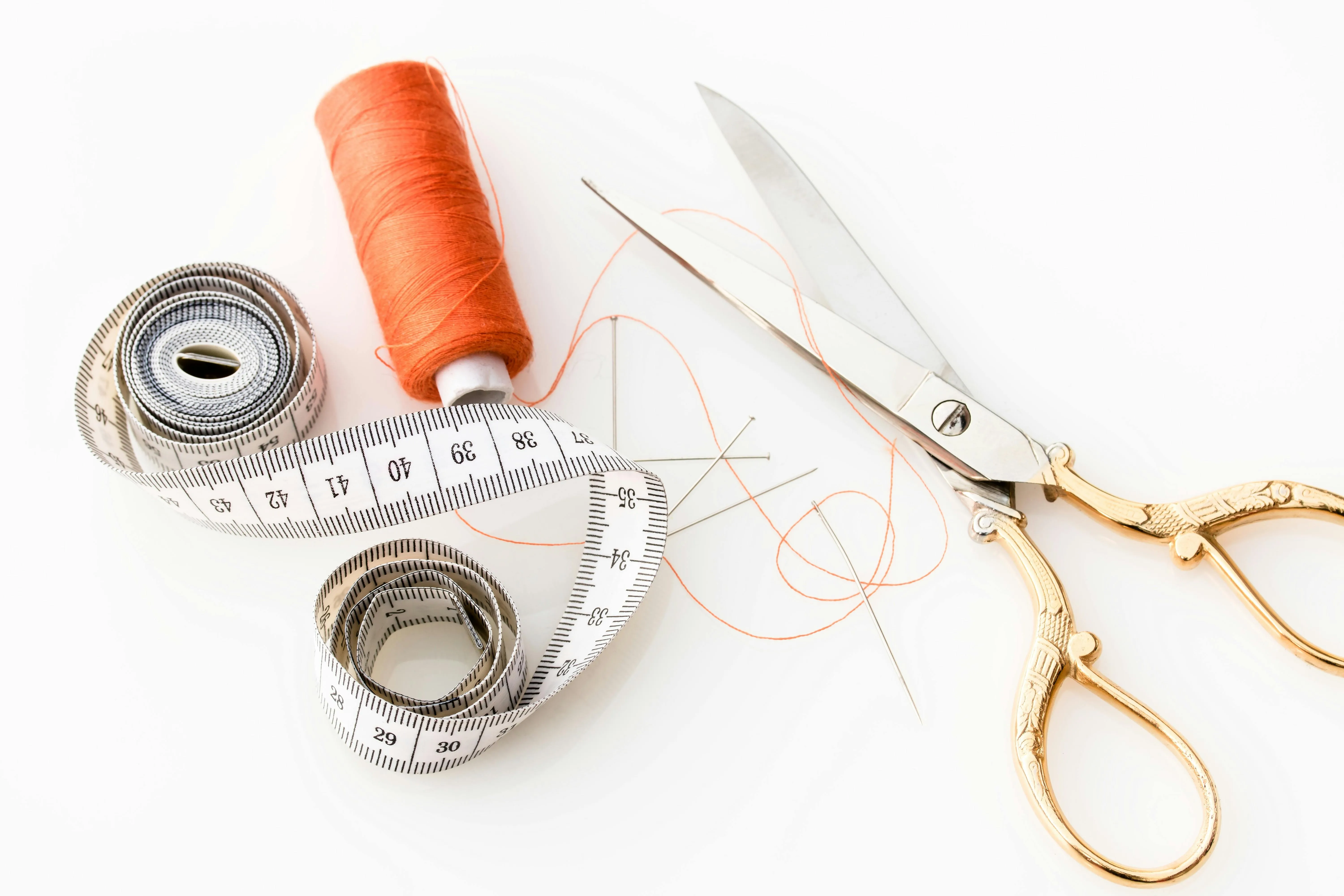 Tools for clothes tailoring. Scissors, thread and a tape measure.